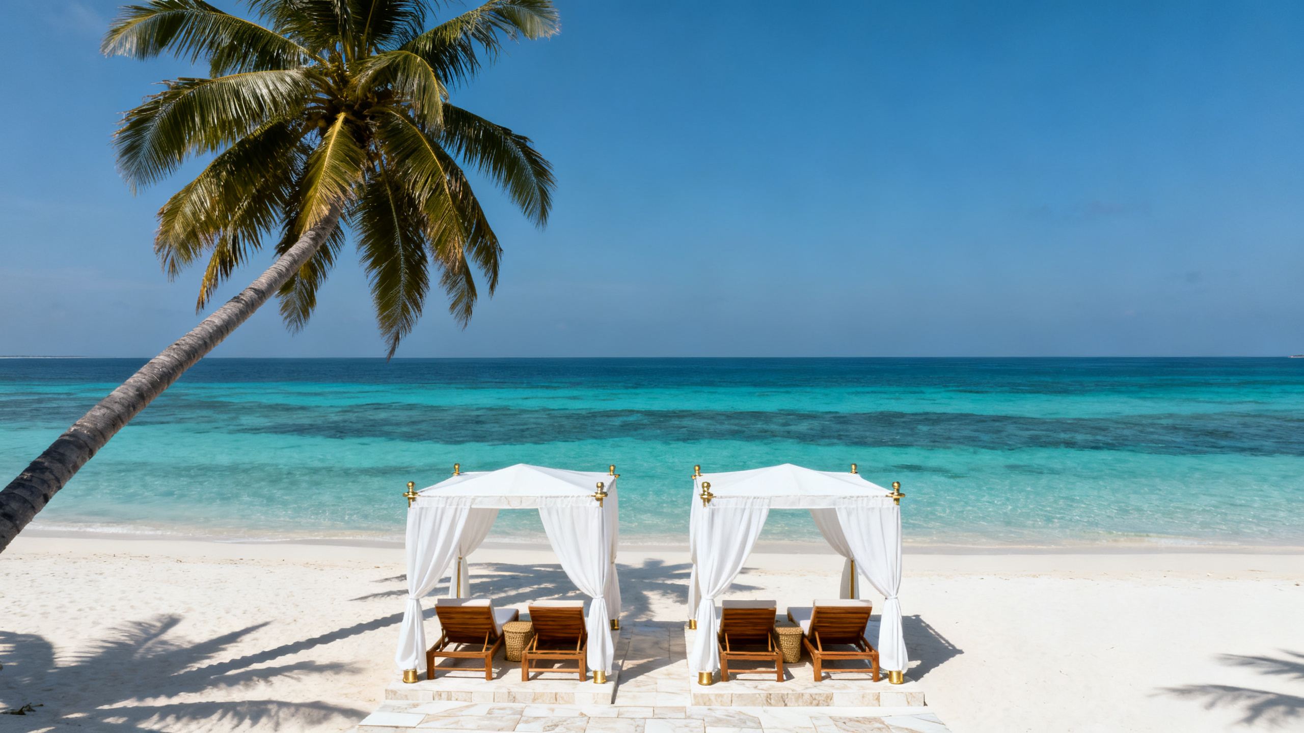 Private white-sand beach in layered turquoise water, leaning palms and canvas cabanas.